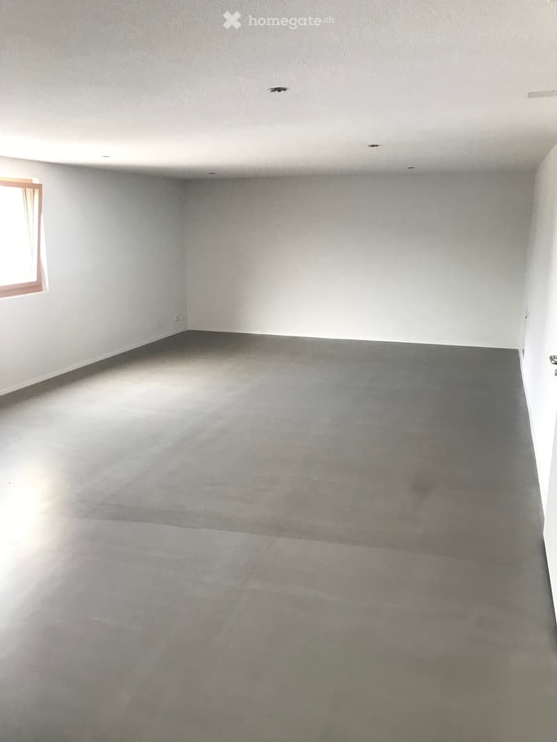 Empty room with white walls, gray floor, and a window on the left wall.