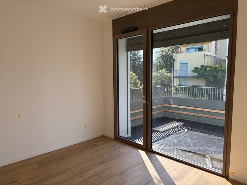 Empty room with wooden flooring and large sliding glass doors leading to a balcony area.