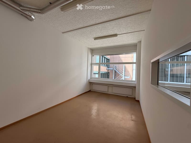 empty room, white walls, brown floor, large windows, view of building outside