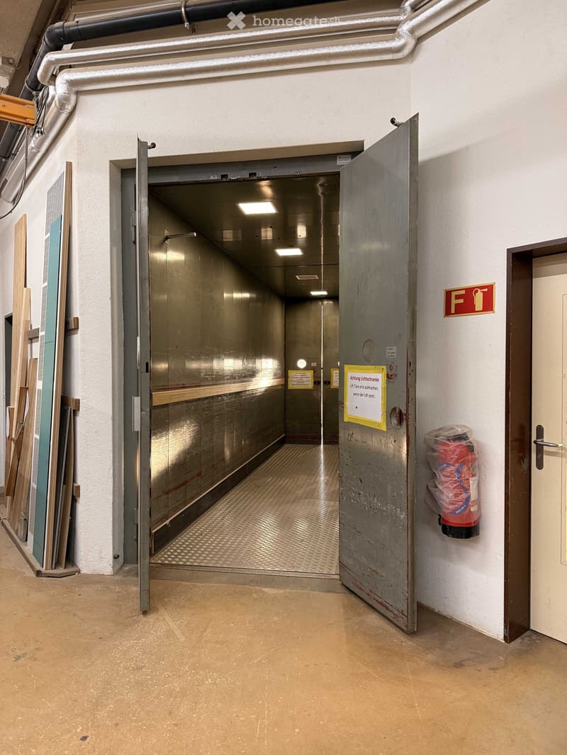 Open metal door, metal floor, white walls, fire extinguisher, sign