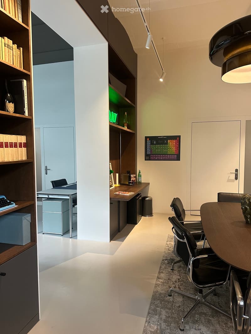 modern office room with white walls, wooden desk, black chairs, bookshelves, carpet, modern lighting, periodic table poster