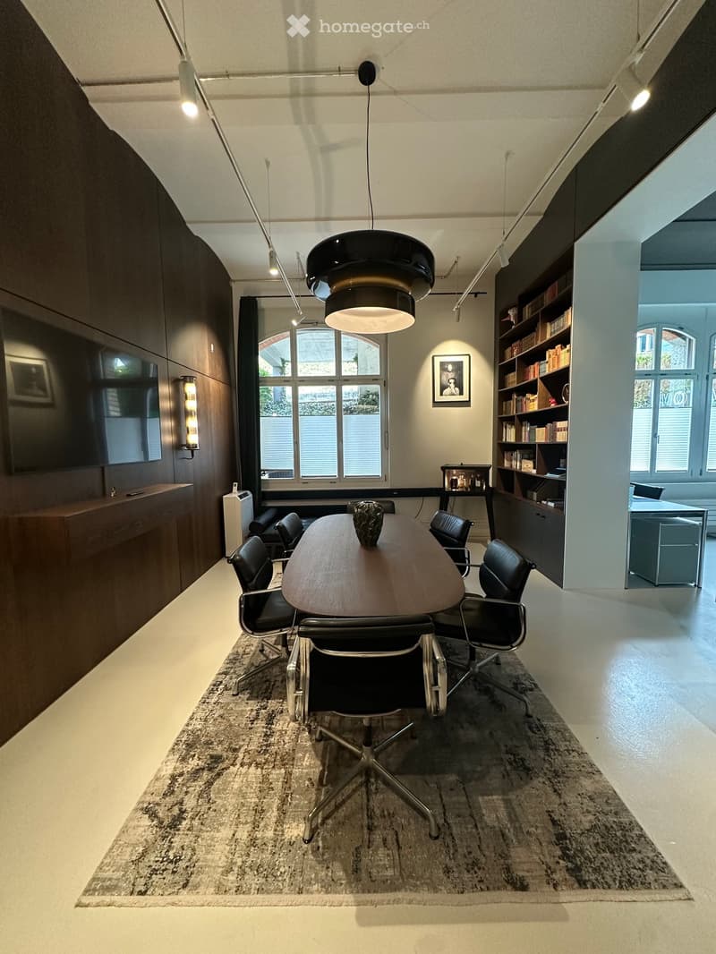 modern office room with a large table, black chairs, wooden wall, bookshelves, and a TV