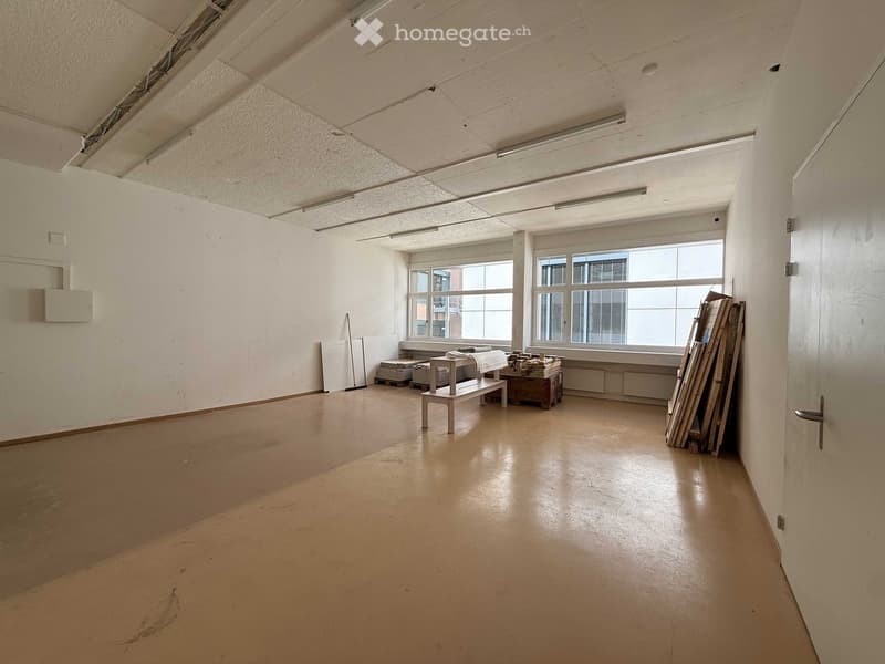 Empty room with white walls, beige floor, large windows, and ceiling lights