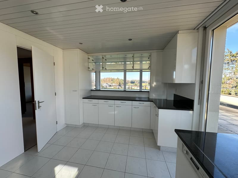 modern kitchen with white cabinets, black countertops, large windows, tiled floor