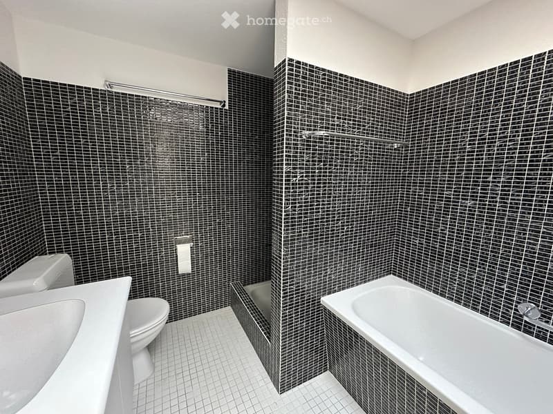 Bathroom with black and white tiles, white bathtub, white sink, white toilet, shower area