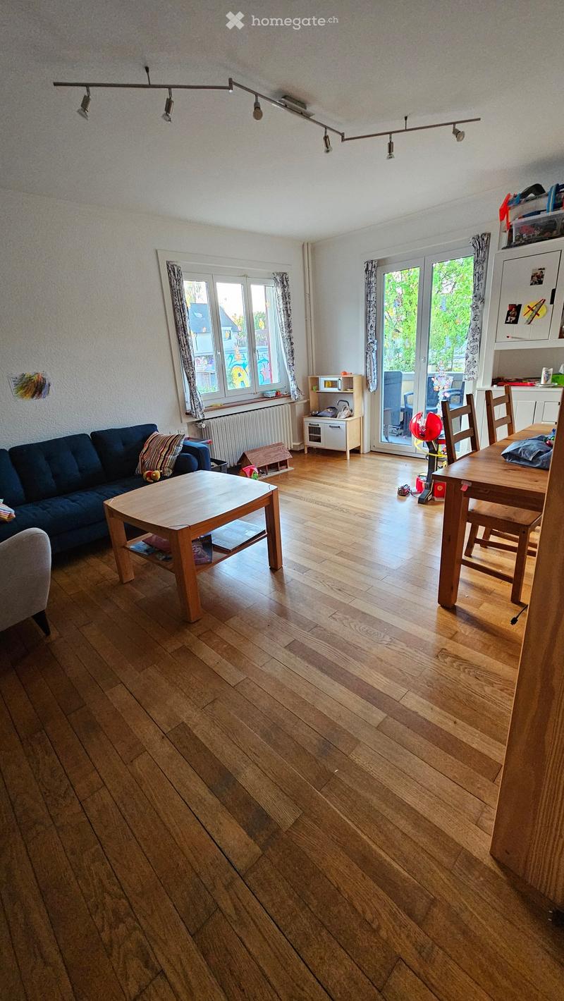 Spacious living room with wooden floors, a blue couch, a coffee table, and a dining table with chairs.