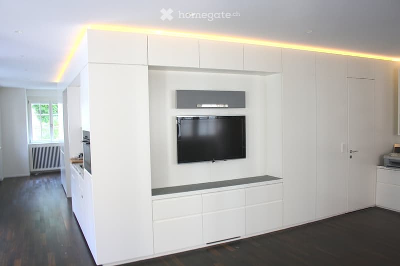 Modern room with white cabinets, a flat-screen TV, and a printer on a cabinet.