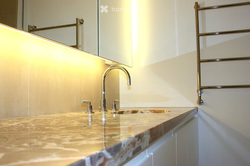 Bathroom with a marble countertop, a sink with a faucet, a mirror, and a towel rack.
