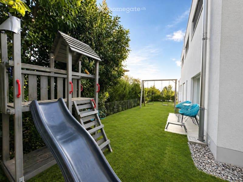 Outdoor area with a slide, swing, and chairs on a patio.