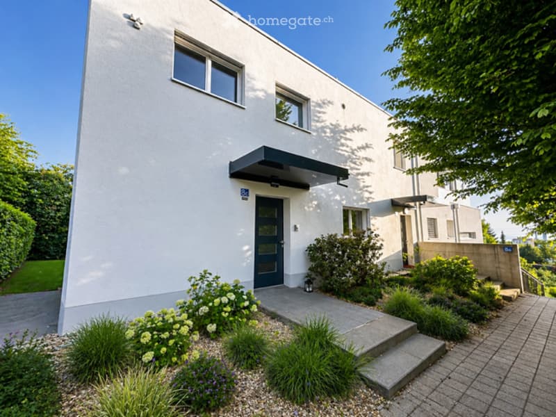 Modern white house with a black entrance canopy, glass windows, and a paved walkway.