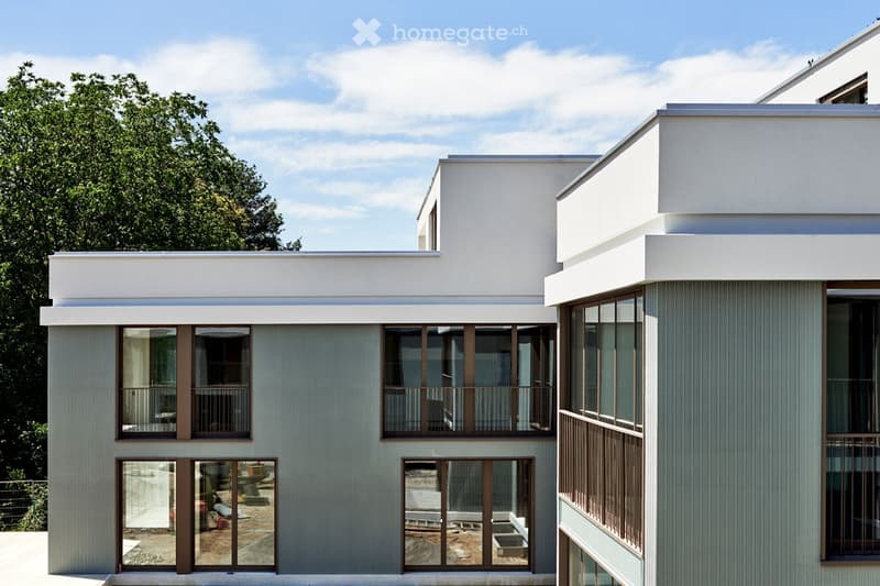 Modern house with white exterior, large glass windows, and balconies.