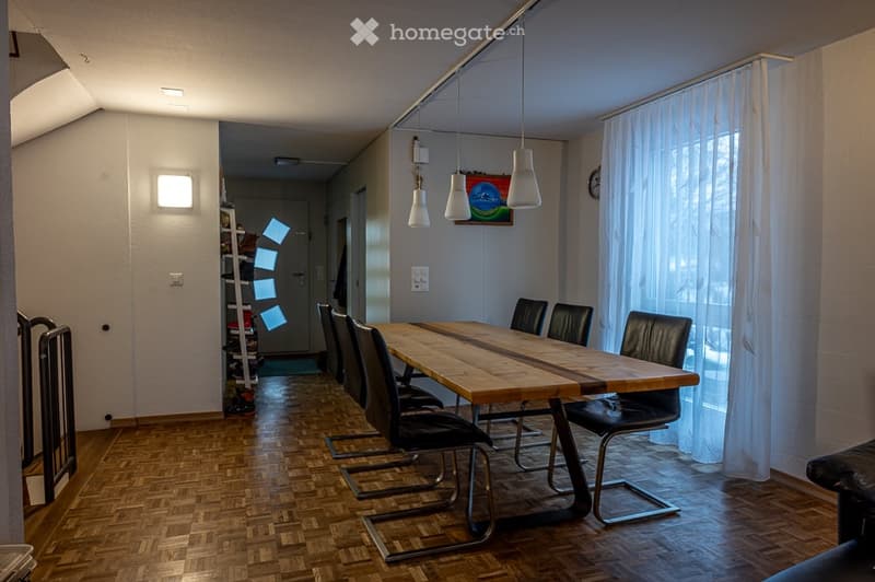 Dining area with wooden table, black chairs, lamps, and a painting on the wall.