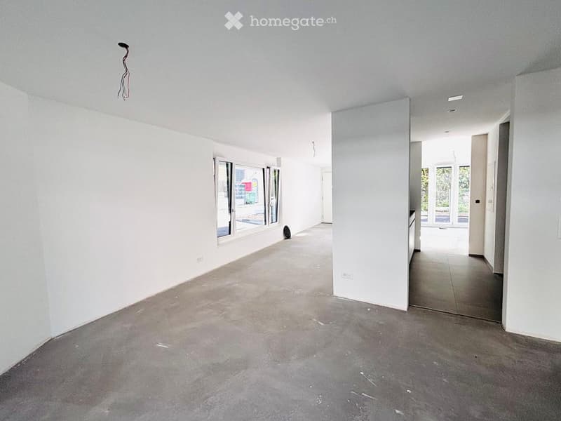 Empty room with white walls, concrete floor, and large windows. No furniture or equipment present.