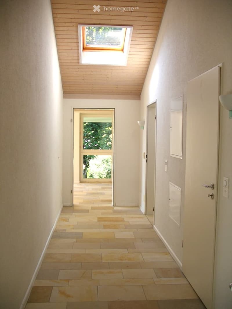 Empty corridor with wooden ceiling, tiled floor, and a skylight.