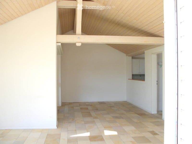 Empty room with white walls, wooden ceiling, and tiled floor. No furniture or equipment.