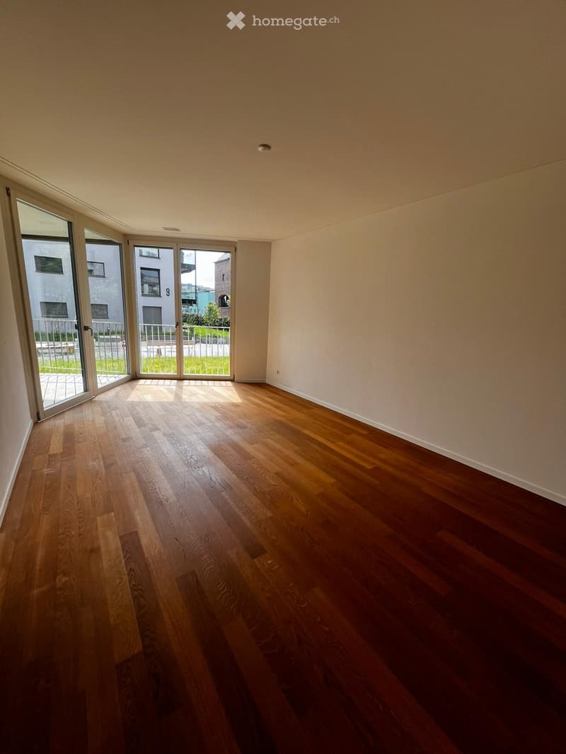 Empty room with hardwood floors, white walls, and large glass doors leading to a balcony.