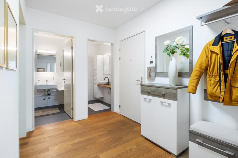 Entrance hallway with a closet and mirror, leading to a bathroom with sink and a small bedroom with a built-in wardrobe and a sink.