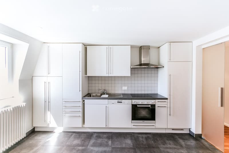 modern kitchen with white cabinets, black countertops, stainless steel appliances, tiled backsplash, and a window