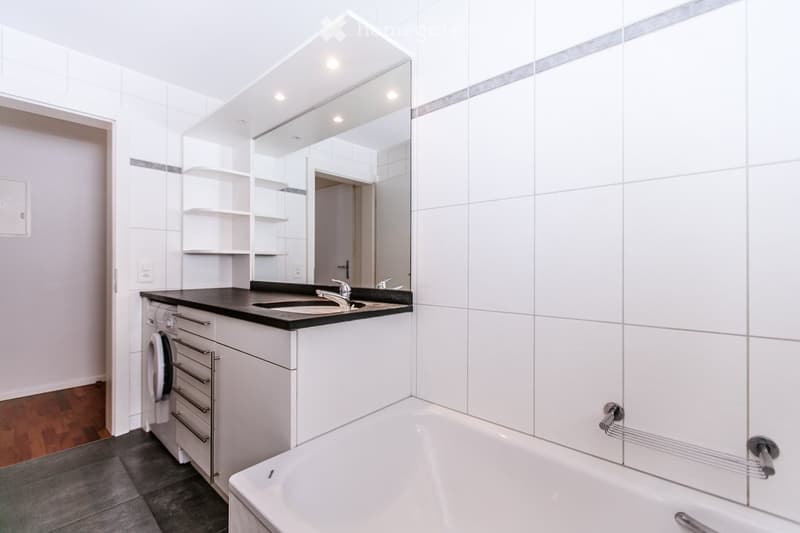white tiles, bathtub, sink, mirror, washing machine, wooden floor