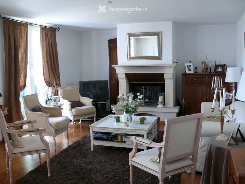 white walls, fireplace, white furniture, wooden floor, large windows, mirror, TV, coffee table, flowers