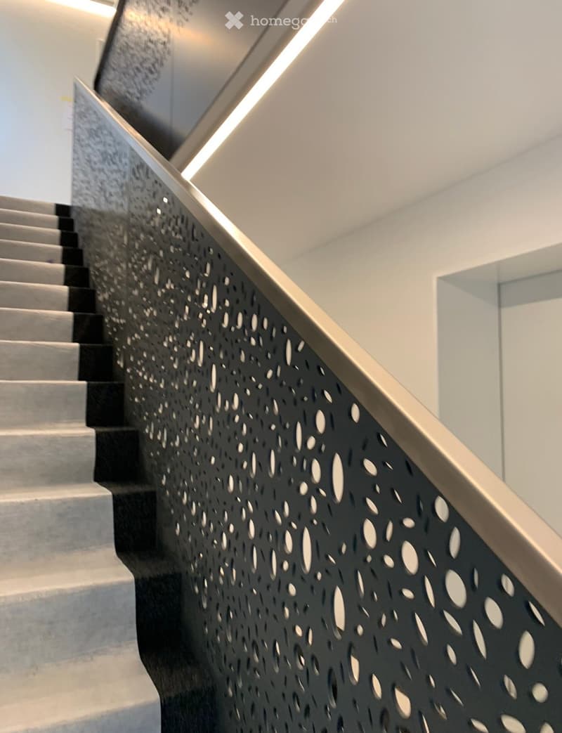 Corridor / Hallway. Modern staircase with a black perforated handrail and white steps.
