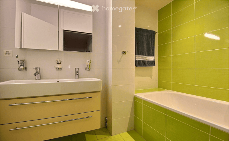 Modern bathroom with a double sink, mirror cabinet, bathtub, and a towel hanging on the wall.