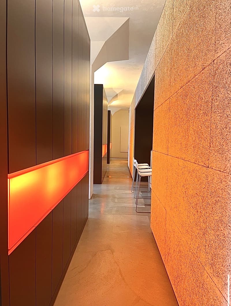 long hallway with brown and orange walls, wooden floor, chairs