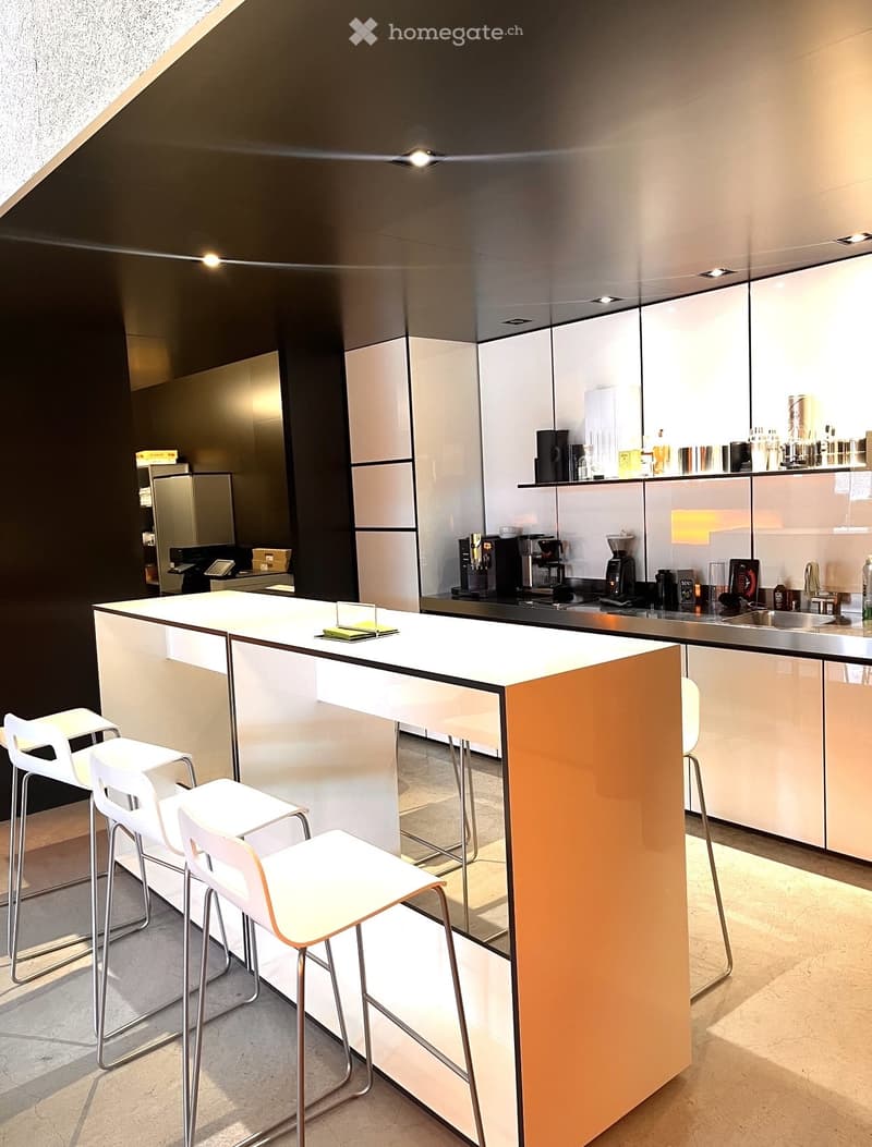 modern kitchen with white countertops, black and white cabinets, stainless steel appliances, bar stools, and a central island