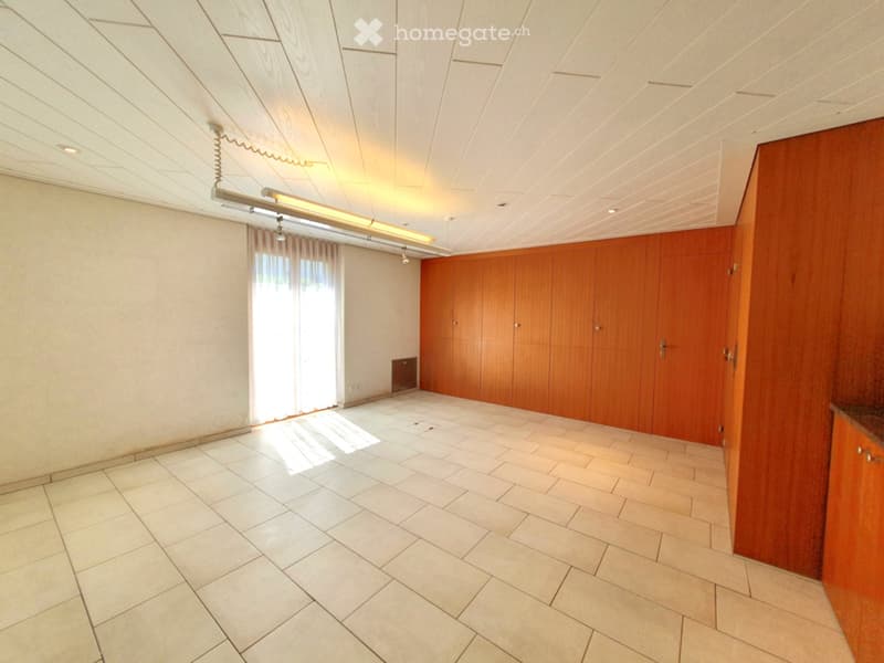 Empty room with white tiled floor, white walls, wooden cabinets, and a window with white curtains.