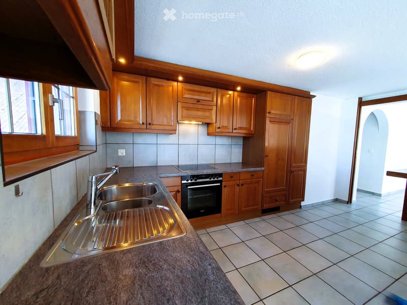 Modern kitchen with wooden cabinets, granite countertop, stainless steel sink, and built-in oven.