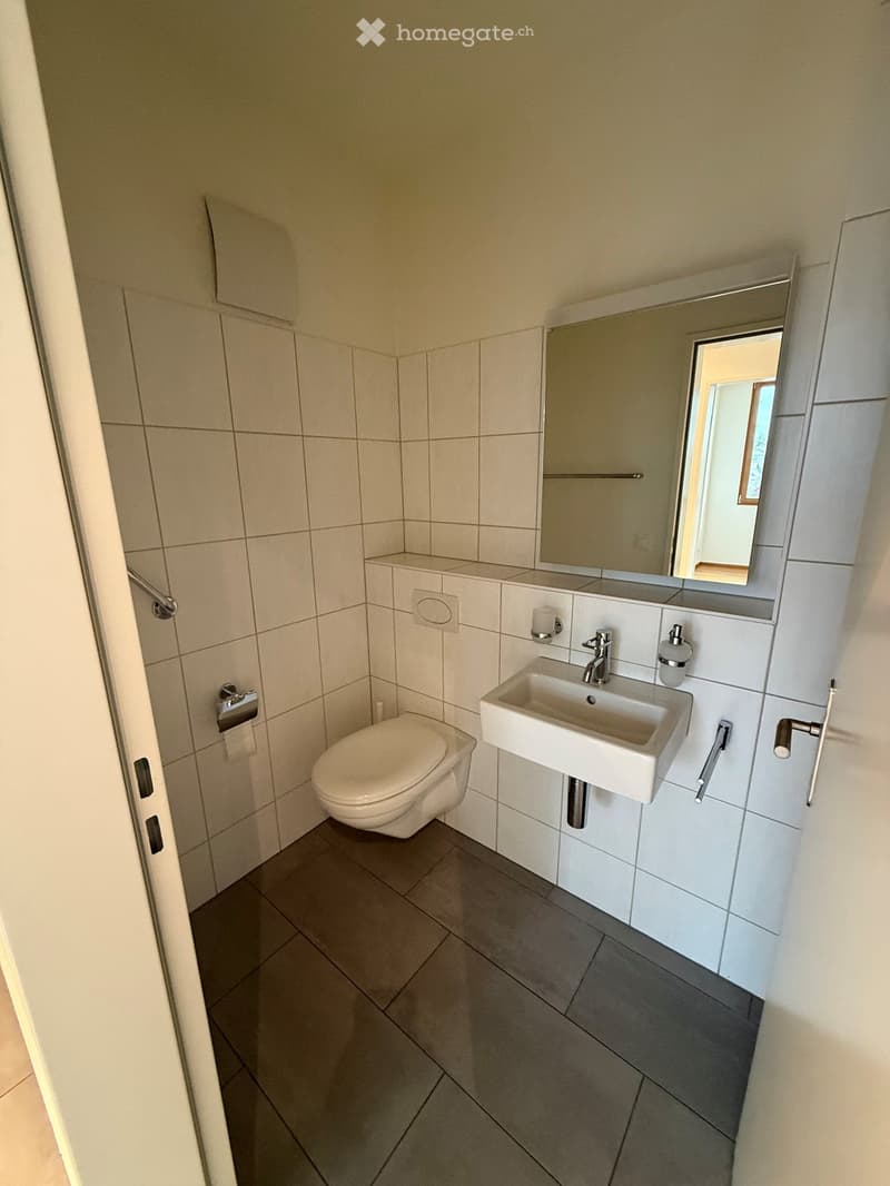 small bathroom with toilet, sink, mirror, and tiled floor