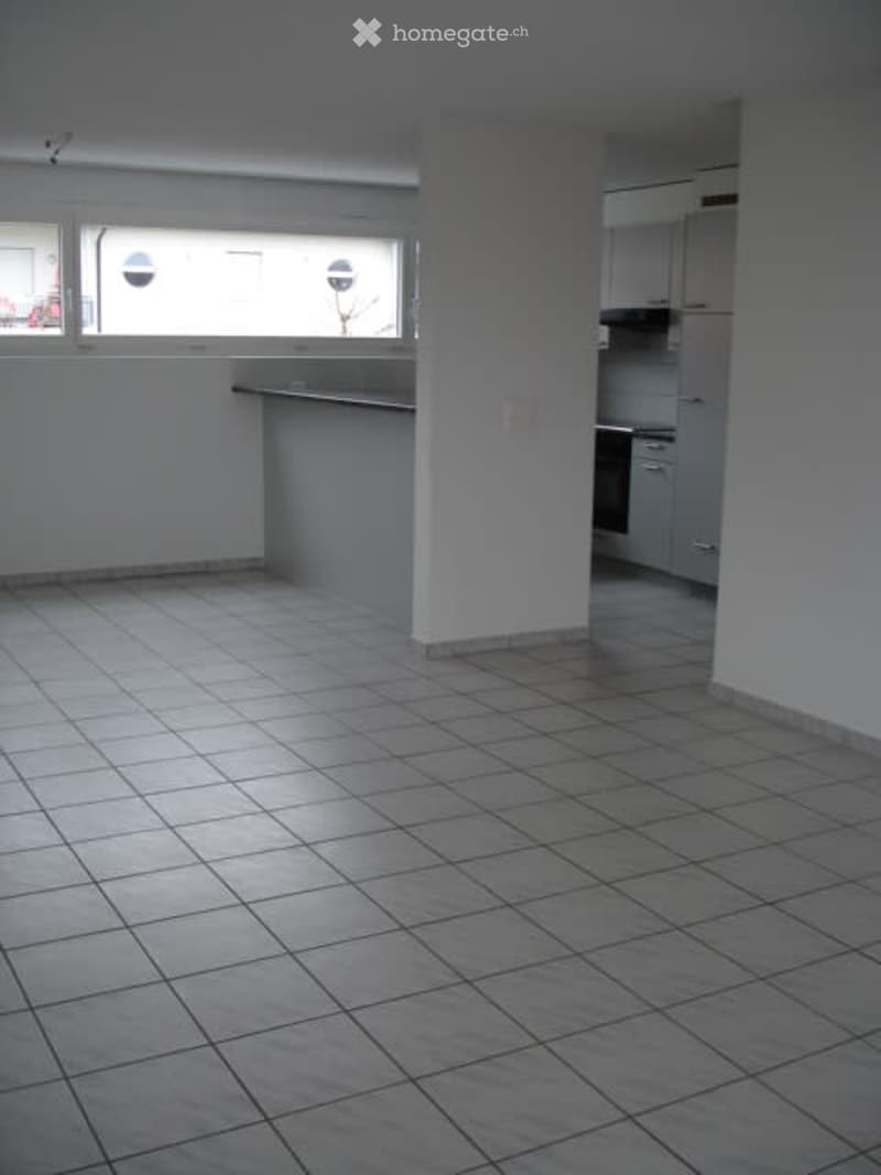 large empty room with tile floor, counter, kitchen area, windows