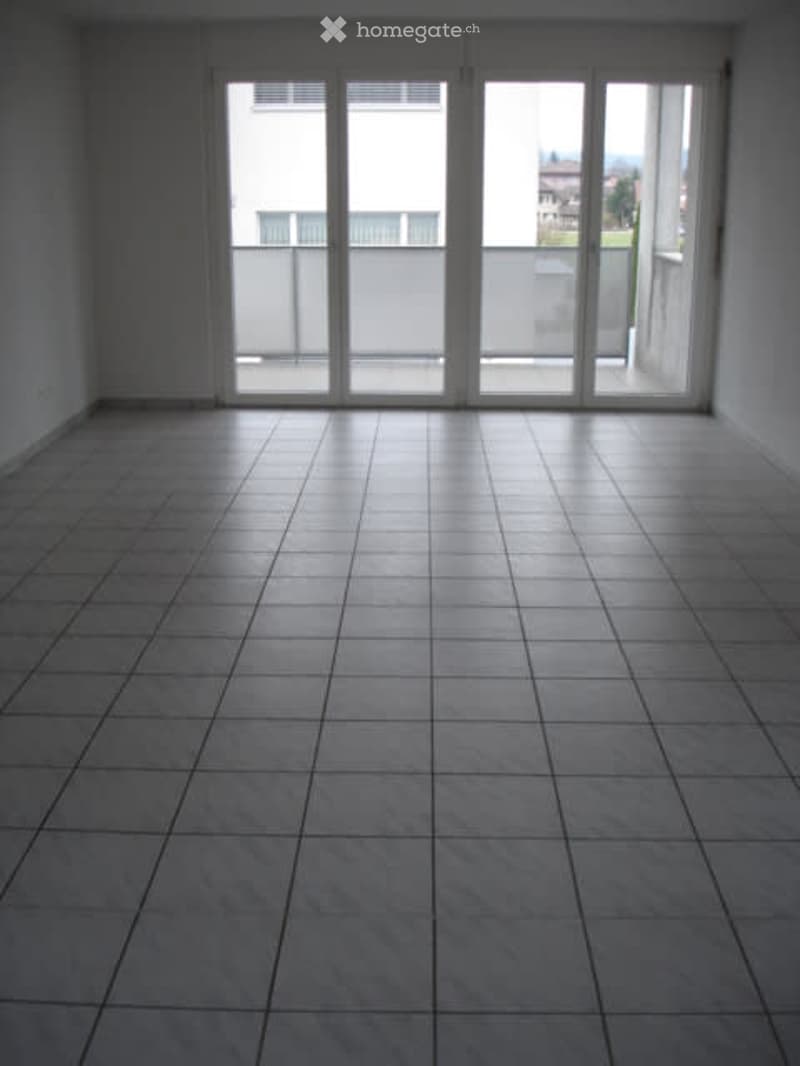 Empty room, white tile floor, large sliding glass doors, balcony, neutral lighting