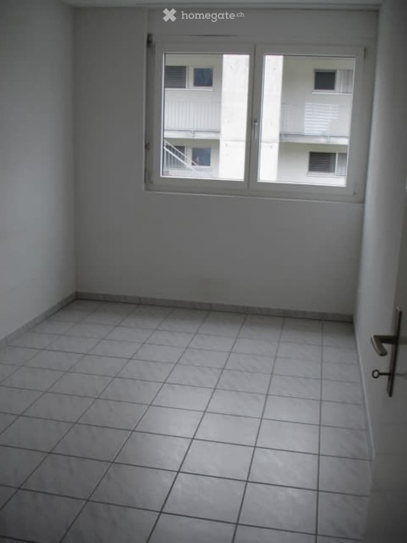 Empty room with white tiles and windows facing a balcony