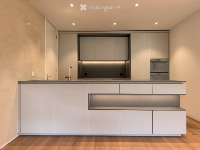 Modern kitchen with white cabinets, a gray countertop, a sink, a faucet, and built-in ovens.