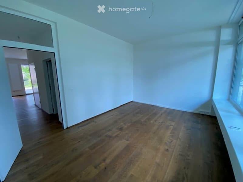 Empty room with hardwood floors, white walls, and a window.
