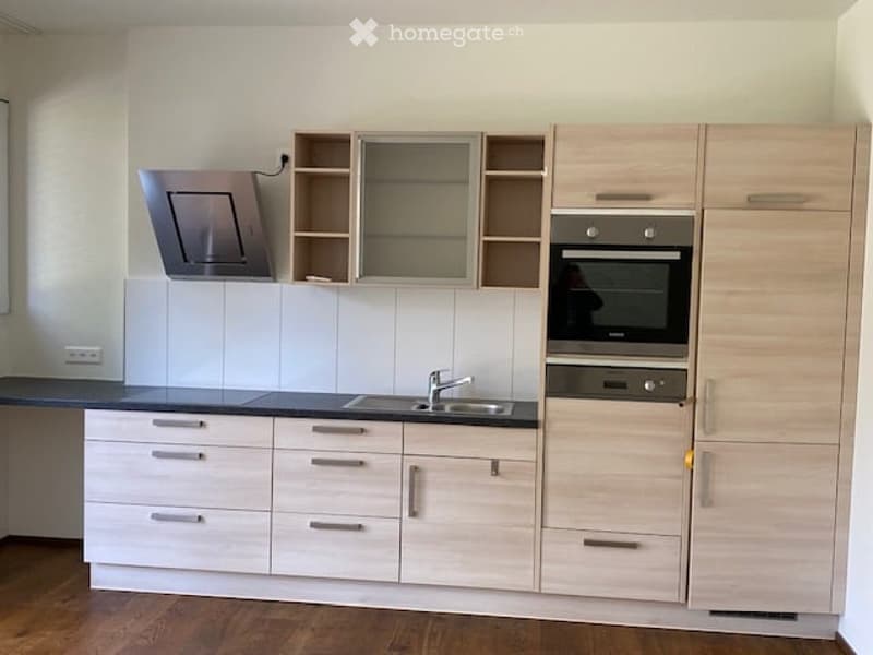 modern kitchen with wooden cabinets, black countertops, stainless steel sink, oven, and dishwasher