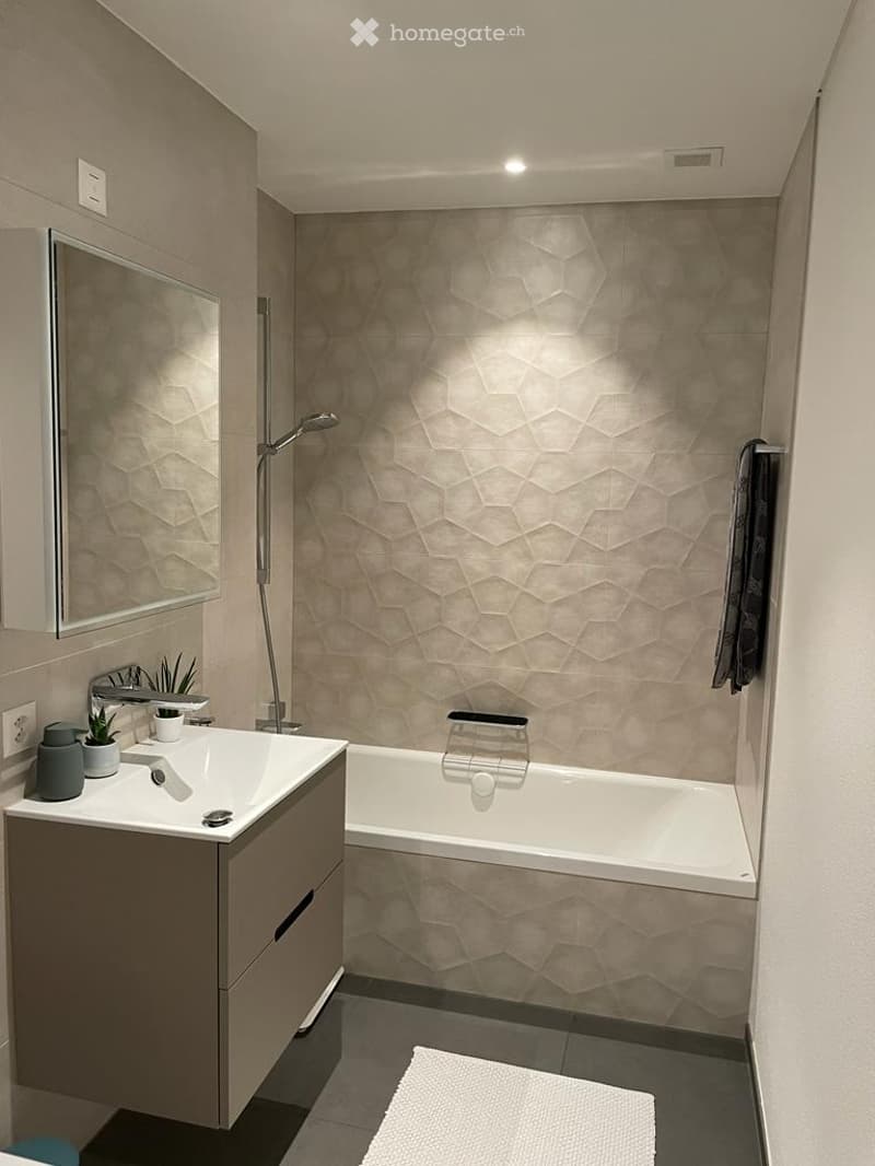 modern bathroom with bathtub, sink, mirror, and geometric wall tiles