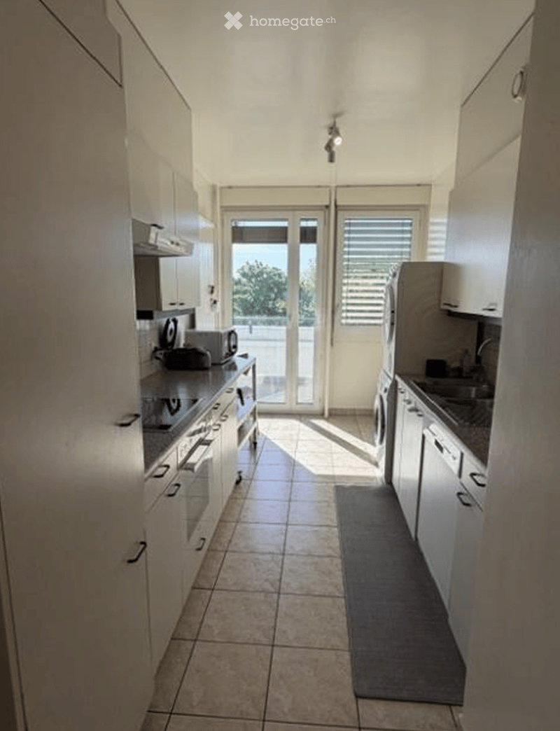Modern kitchen with white cabinets, tiled floor, and stainless steel appliances.