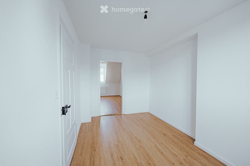 Unfurnished Room. Completely empty room with white walls, wooden floor, and a door. No furniture or equipment.