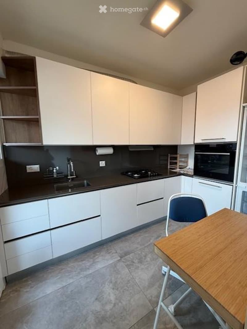 Kitchen. Modern kitchen with white cabinets, black countertops, a wooden table, and a blue chair.