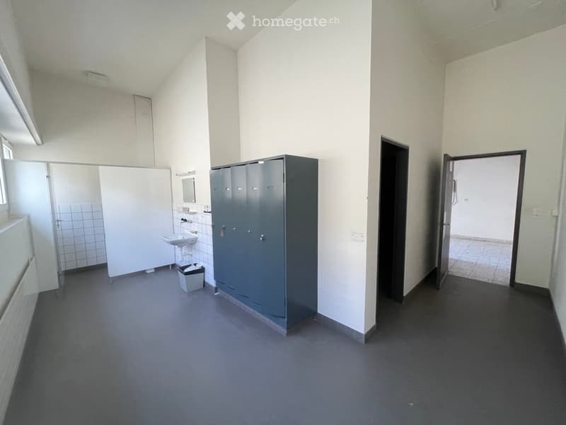 empty room with a sink, toilet, storage cabinets, doors, trash can, tiled wall