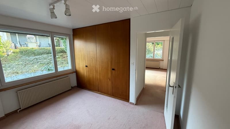 wooden wardrobe, white walls, radiators, carpeted floor, large windows