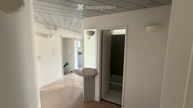 an interior room, hallway, tile floor, empty, white walls, ceiling lights, round mirror, open door to bathroom