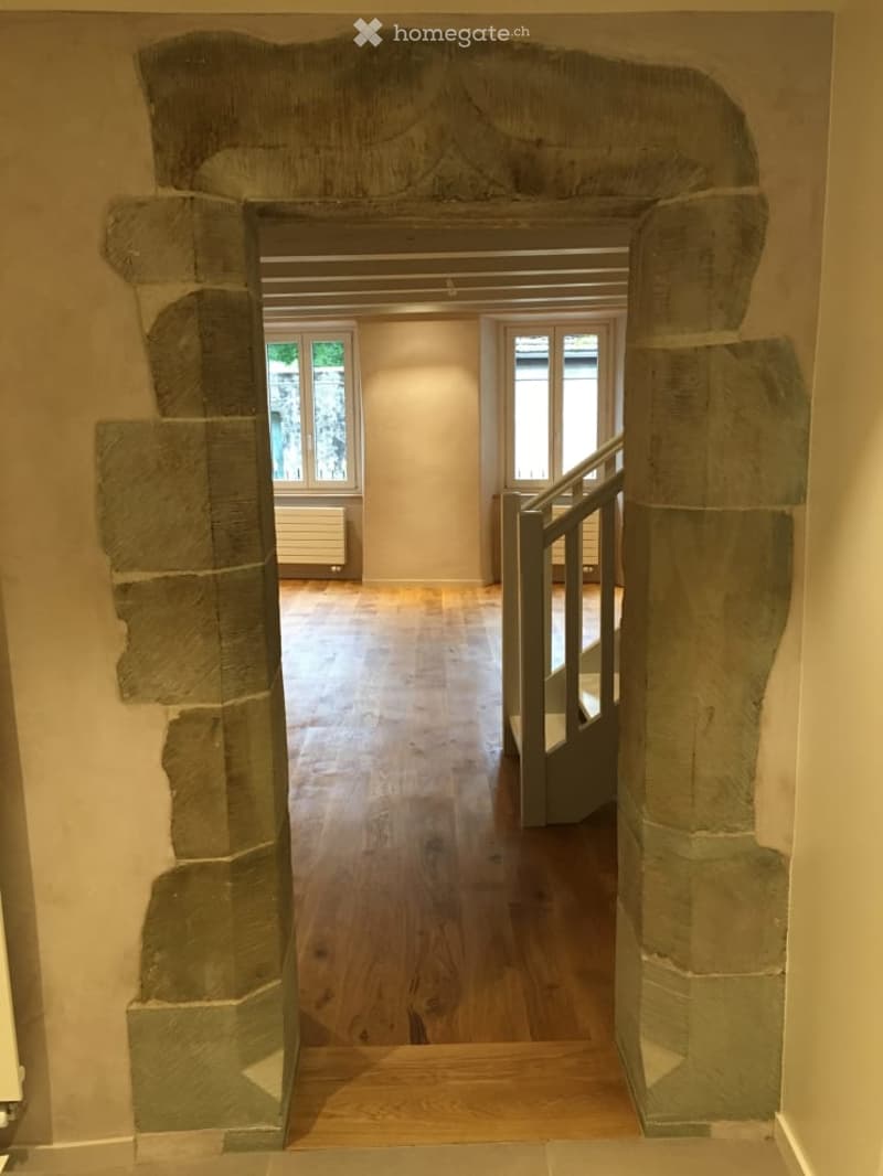 {"visible_features": ["Raised ground floor"],    "type": "Room",    "description": "stone archway, wooden floor, white painted wall, staircase, windows",    "localized_descriptions":        {        "EN": "Room: stone archway, wooden floor, white pai