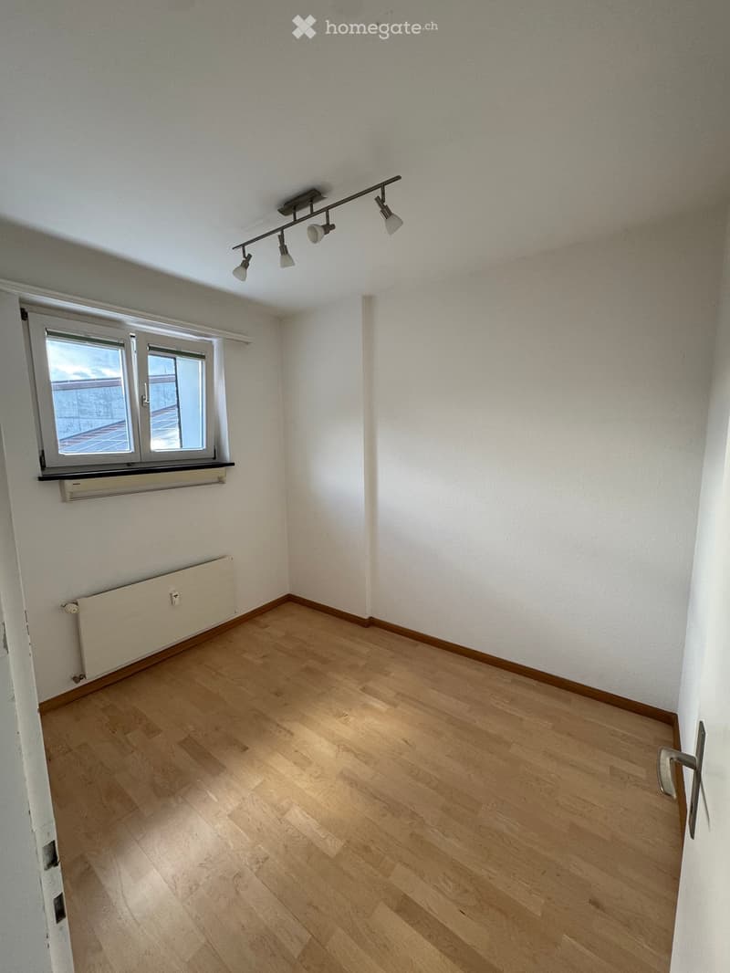 Completely empty room with white walls, wooden floor, and a window with a white frame.