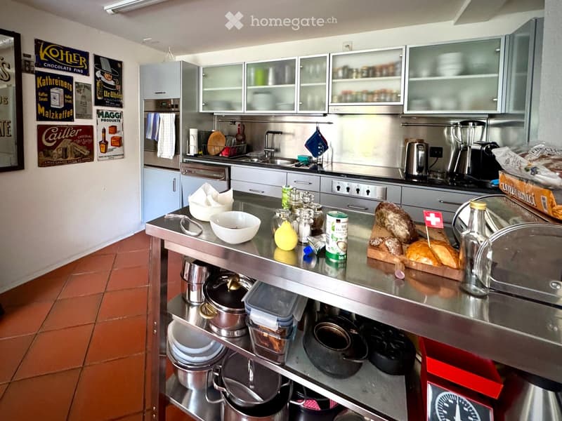 kitchenette with large stainless steel counter top, open kitchen shelves, gas stove, double sink, dishwasher