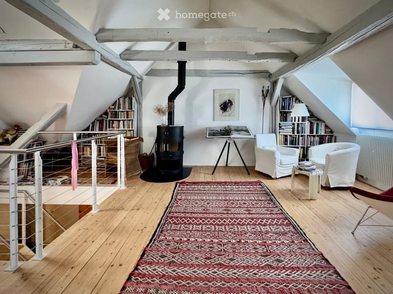 white walls, wooden floor, bookshelves, fireplace, white chairs, metal staircase, radiator