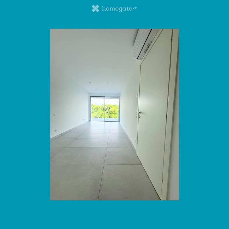 Unfurnished Room. Empty room with white walls, tiled floor, and a sliding glass door leading to a view of trees.