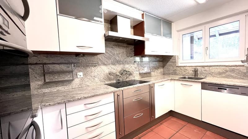 Modern kitchen with granite countertops, stainless steel appliances, white cabinets, and tiled flooring.
